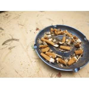  An Ash Tray with Many Cigarette Butts on a Stained Counter 
