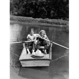  Boy and Girl in Row Boat on Lake, Each Rowing With an Oar 